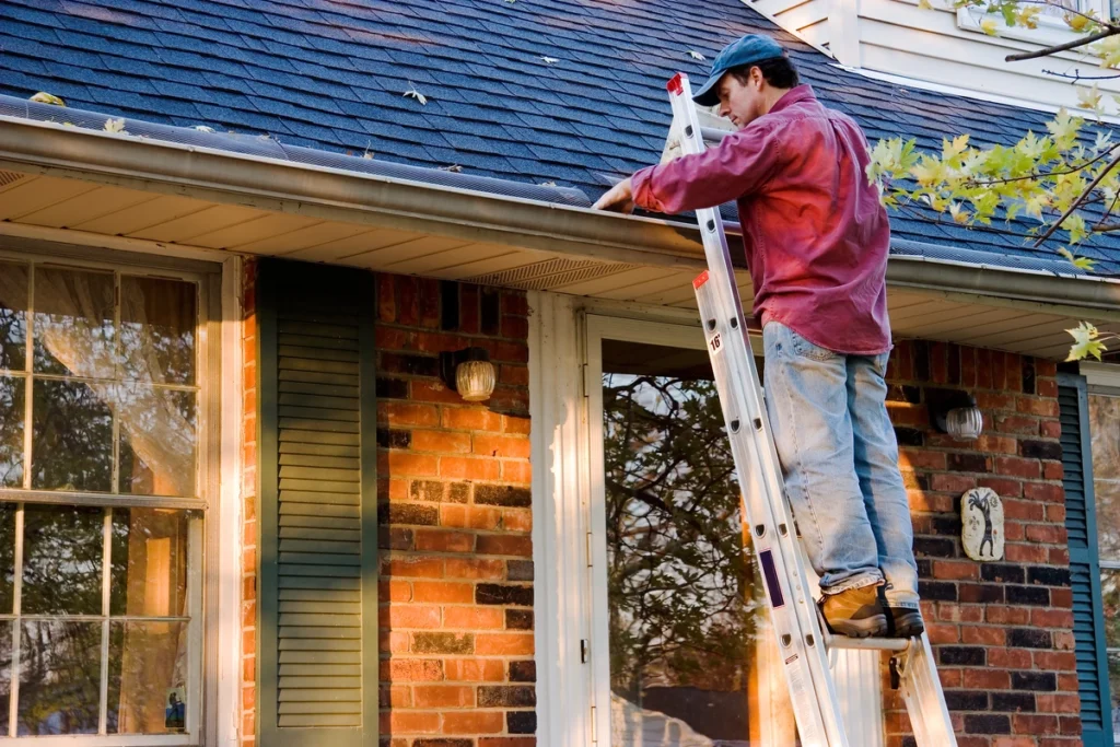 man performing shingle roof maintenance on his home