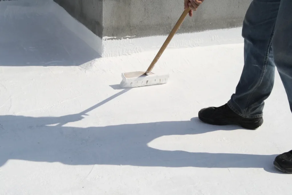 a worker applying white roof coating